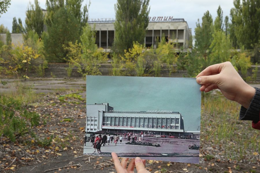 PRIPYAT, UKRAINE - SEPTEMBER 29:  An assistant holds up a photo showing the city of Pripyats main square and the Energetik cultural center before 1986 at the same site that today is abandoned and overgrown with trees on September 29, 2015 in Pripyat, Ukraine. Pripyat lies only a few kilometers from the former Chernobyl nuclear power plant and was built in the 1970s to house the plants workers and their families. On April 26, 1986, technicians at Chernobyl conducting a test inadvertently caused reactor number four to explode, sending plumes of highly radioactive particles and debris into the atmosphere. Authorities evacuated 120,000 people from the area, including 43,000 from Pripyat. Today Pripyat is a ghost-town, its apartment buildings, shops, restaurants, hospital, schools, cultural center and sports facilities derelict and its streets overgrown with trees. The city lies in the inner exclusion zone around Chernobyl where hot spots of persistently high levels of radiation make the area uninhabitable for thousands of years to come.  (Photo by Sean Gallup/Getty Images)