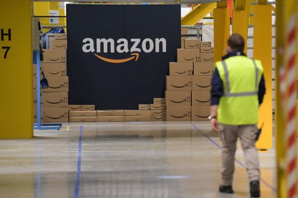 An US giant Amazon employee passes by its logo on the opening day of the new distribution center in Augny, eastern France, on September 23, 2021. (Photo by SEBASTIEN BOZON / AFP) (Photo by SEBASTIEN BOZON/AFP via Getty Images)